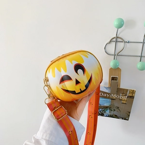 Detail of pumpkin-shaped crossbody bag with smiling face and wide printed shoulder strap