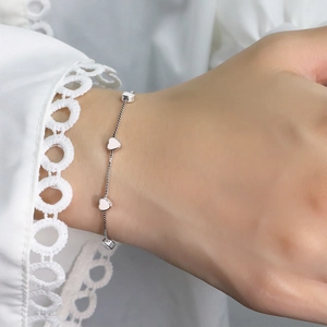 Detailed view of silver heart-shaped charms on a delicate metal chain worn on wrist