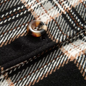 Nahaufnahme von braunem Karo-Wollstoff mit hochwertigem Schildpatt-Resin-Knopfdetail