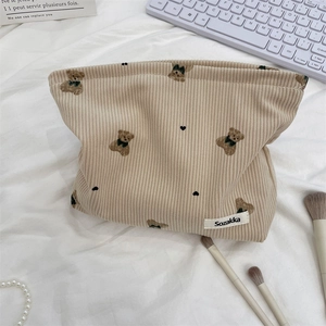 Detail of beige corduroy pouch with bear embroidery and Sozakka label on desktop