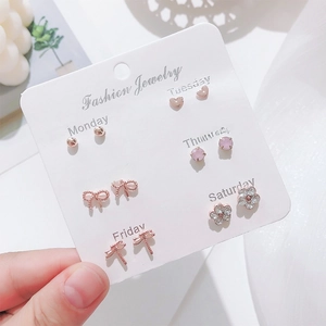 Detail of six pairs of rose gold earrings on a weekly card with hearts and crystals