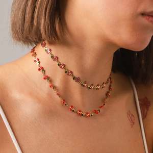 Double layered gold stainless steel necklace with pink and red cherry pendants on a model