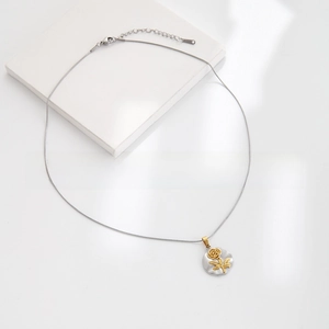 Macro shot of silver chain with a golden rose pendant on a minimalist white background