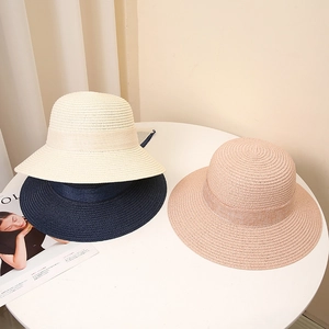 Wide brim paper straw sun hats with bows in cream, navy, and pink for beach sun protection