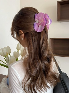 Detail of purple orchid hair claw with pearl accent on wavy hair for elegant styling