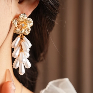 Gros plan de boucles d'oreilles fleur dorée avec perles gouttes blanches sur un modèle