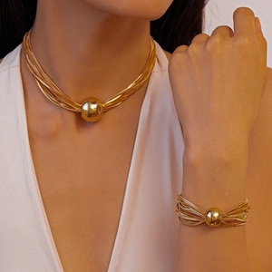 Close-up of multi-strand gold chain necklace and bracelet set with large polished gold beads