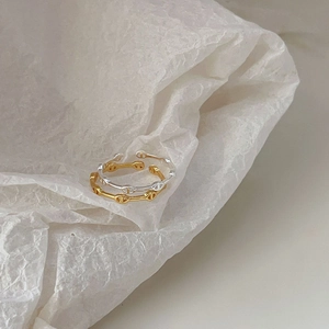 Close-up of gold and silver pig nose anchor link open rings on white textured paper