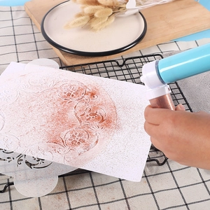Manual cake airbrush pump applying cocoa powder onto a cake through a stencil