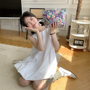 Close-up of a floral cotton makeup bag held by a model in a sunlit minimalist room