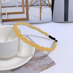 Close-up of yellow beaded braided headband with twisted texture on a white saucer