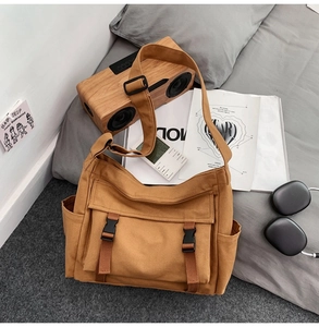 Vue détaillée du sac bandoulière en toile marron avec sangle réglable sur un lit douillet