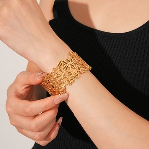 Detailed view of wide gold clover hollow bracelet worn on wrist with intricate cutouts