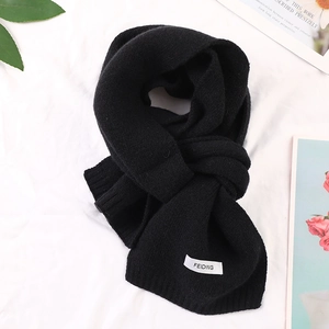 Close-up of black knitted winter scarf featuring soft texture and stylish white fabric label