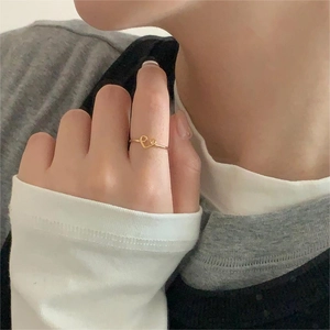 Detailed close-up of a minimalist gold heart-shaped ring worn by a model in daily wear