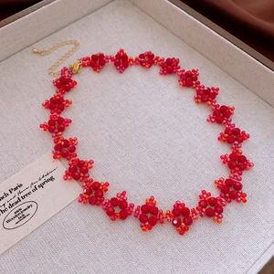 Détail du collier ras du cou à fleurs rouges avec chaîne d'extension dorée sur plateau