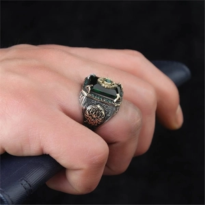 Detail of vintage silver ring with green gemstone and gold embossed side patterns