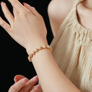 Detail of a double-layered heart zircon bracelet in gold finish worn on a wrist