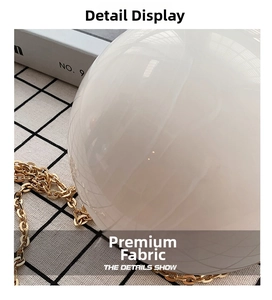 Detailed macro shot of white pearlescent sphere bag with elegant gold chain strap