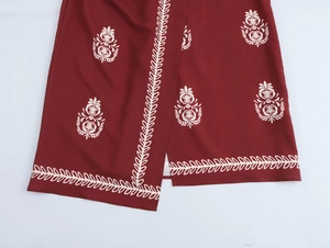 Detail of dark red wrap dress featuring white floral leaf embroidery and side slit detail