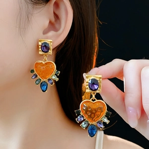 Detail of vintage heart earrings with colorful crystals and purple stones worn by model