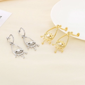 Detail of bohemian evil eye drop earrings in gold and silver with shell pearl inlay