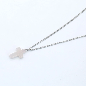 Detail shot of a delicate silver chain with a translucent pink natural stone cross pendant