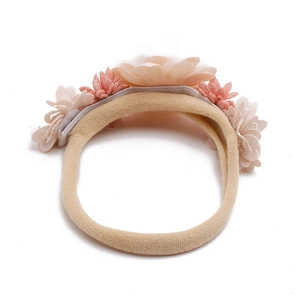 Detail of soft fabric flowers in pink and coral on a beige baby headband for girls