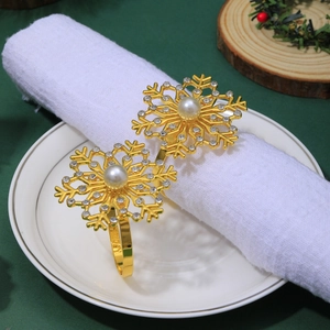 Close-up of golden snowflake napkin rings with pearls and rhinestones on white linens