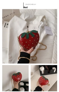 Detail of red strawberry heart bag with gold studs and green leaf accents