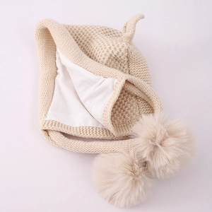Detail of baby winter knit hat with soft lining and fluffy pom-pom decorative ears