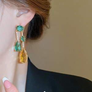 Détail de boucles d'oreilles plaquées or avec zircons en cascade jaunes et verts