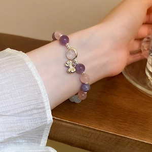 Detail of beaded bracelet with butterfly pendant worn on wrist against a wooden background