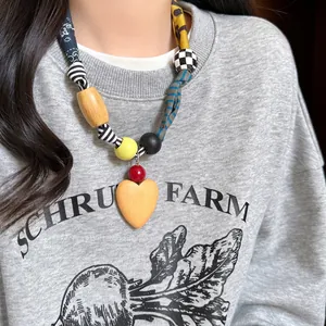 Detail of fabric print heart necklace with wooden pendant and colorful beads on a model