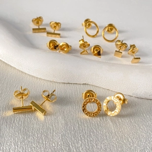 Close-up of gold hammered geometric stud earrings set in various minimalist shapes