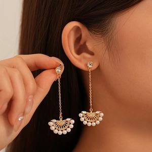 Detailed view of long gold tassel earrings with pearls and rhinestones on a female model