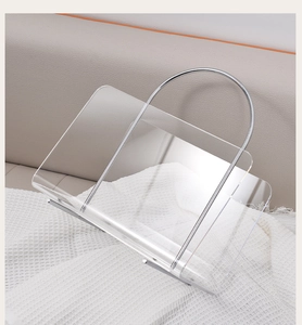 Detail of transparent acrylic magazine rack with polished silver metal handle on white rug