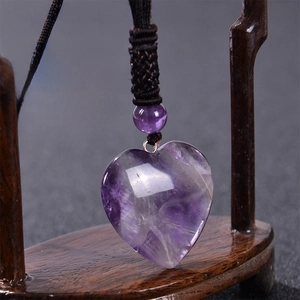 Detail of heart shape amethyst pendant with adjustable woven rope on wooden stand