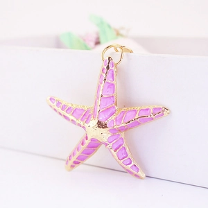 Pink and purple colorful starfish keychain with golden metal edges on a gift box