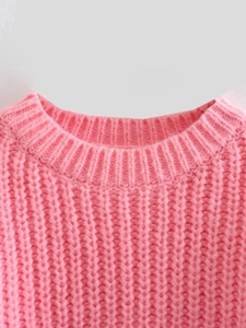 Dettaglio del girocollo a coste e della trama a maglia grossa di questo maglione rosa