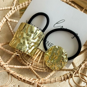 Minimalist golden hammer-textured metal hair rings set in a woven basket