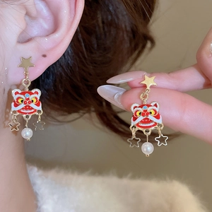 Détail de boucles d'oreilles lion danse en émail rouge avec perles et pompons