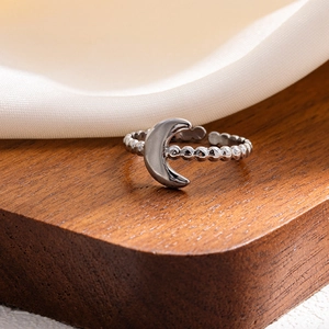 Detail of silver crescent moon ring with beaded band texture on wooden stand