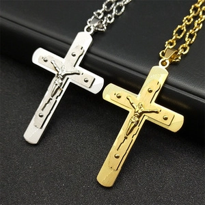 Gros plan de pendentifs croix en acier inoxydable or et argent avec gravure de Jésus