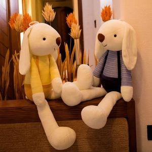Plush long-eared rabbits wearing striped outfits sitting on a wooden table decoration