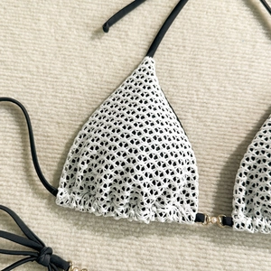 Detail of white crochet bikini top with black ties and gold pearl ring hardware