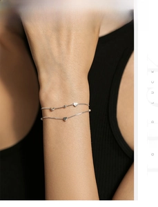 Detail of silver S925 double-layer heart bracelet on wrist with polished beads and chain