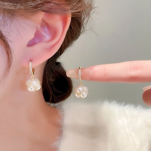 Close-up of elegant gold plated pearl earrings with sparkling crystals worn by a model
