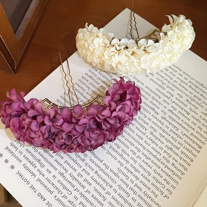 Detail of fabric flower hair pins in purple and cream white on a vintage book