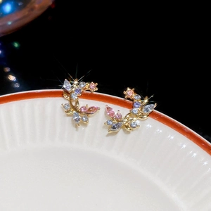 Detailed macro view of sparkling gemstone tree branch stud earrings on a white plate
